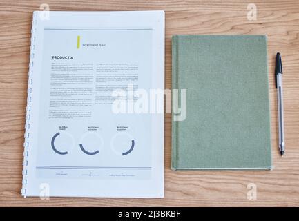 Weve ha preparato il nostro piano di investimento. Scatto ad alta angolazione di documenti e un notebook su una scrivania in un ufficio vuoto durante il giorno. Foto Stock