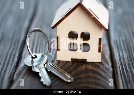 Piccola casa giocattolo con le chiavi sulle tavole di legno marrone Foto Stock