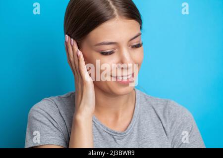 Closeup profilo laterale femmina malato avendo dolore all'orecchio che tocca la sua testa dolorosa. Foto Stock