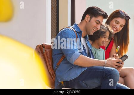 Bambino ragazzo che tiene un lollipop colorato e divertirsi con il suo genitore Foto Stock