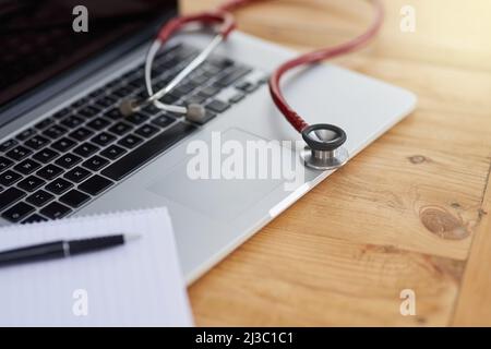 Ricerca delle ultime innovazioni mediche. Primo piano di un notebook, uno stetoscopio e un notebook medico su un tavolo. Foto Stock