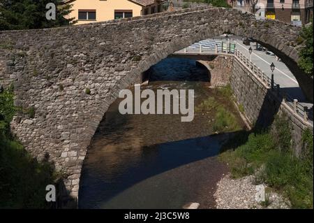 Antico e moderno: Un ponte stradale ora attraversa il fiume Llobregat a la Pobla de Lillet in Catalogna, Spagna, accanto al Pont Vell medievale o Ponte Vecchio, costruito nel 1300s d.C. Il Pont Vell ha ora un unico alto arco posteriore asino, ma potrebbe essere stato un secondo arco e le fondamenta dei pilastri bugnato suggeriscono origini romane. Foto Stock