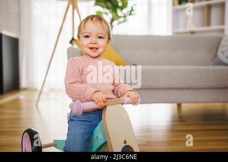 Adorabile bambina imparando a bilanciare la sua prima moto a casa Foto Stock