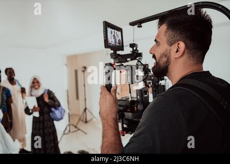 Un videografo in uno studio domestico cattura un gruppo di studenti moderni con una fotocamera professionale. Foto Stock