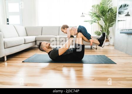 Buon padre che si allena con il suo bambino il bambino guarda qualcuno. Foto Stock