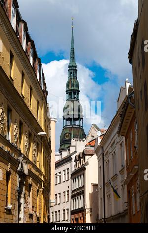Il campanile della Chiesa di San Pietro dietro edifici colorati a riga, Lettonia Foto Stock