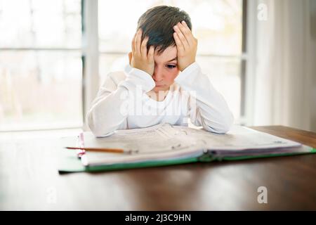 Il bambino pensante annoiò e frustrato e si stanche facendo i suoi compiti Foto Stock