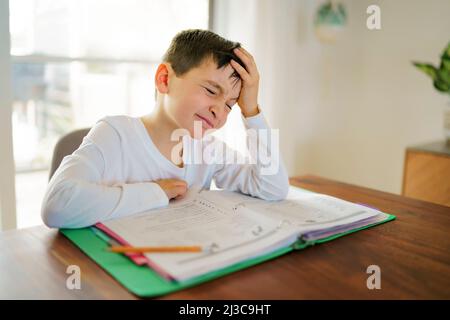 Il bambino pensante annoiò e frustrato e si stanche facendo i suoi compiti Foto Stock