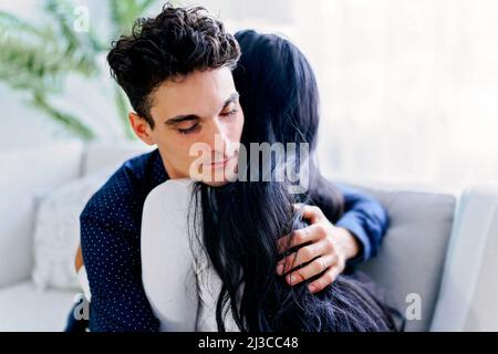 Coppia attraente coccole sul divano di casa in soggiorno Foto Stock