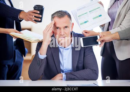 I miei giorni sono pieni di troppe scadenze. Ritratto di un uomo d'affari maturo che osserva sottolineato fuori in un ambiente d'ufficio esigente. Foto Stock