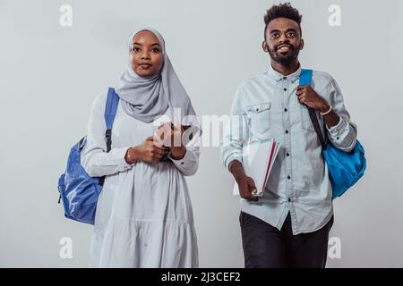 Giovani studenti africani coppia camminando donna indossando tradizionale sudanese musulmano abiti hijab squadra di affari isolato su sfondo bianco. Alta qualità Foto Stock