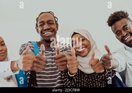 Ritratto di gruppo di studenti africani felici in piedi insieme su uno sfondo bianco e mostrando ok segno pollici su ragazze che indossano il Sudan tradizionale Foto Stock