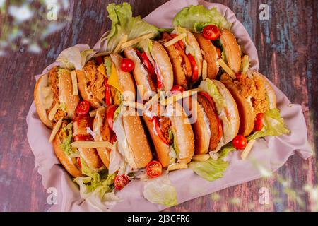 Hamburger diversi visti dall'alto con patatine fritte nel mezzo dei sandwich. Cesti con un panno sotto gli hamburger. Foto Stock