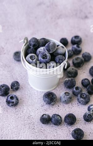 Mirtilli congelati in secchio su fondo di cemento. Frutta di stagione biologica sana sfondo. Cibo biologico. Raccogliendo, preparando cibo per Foto Stock