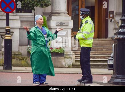 Londra, Inghilterra, Regno Unito. 7th Apr 2022. Un protettore nelle scrub del medico parla ad un ufficiale di polizia. Estinzione i medici della ribellione e gli operatori sanitari hanno bloccato la strada al di fuori del Tesoro HM a Westminster la Giornata Mondiale della Sanità, in protesta contro il finanziamento del governo di combustibili fossili. Diversi manifestanti si sono incollati a barili. (Credit Image: © Vuk Valcic/ZUMA Press Wire) Foto Stock