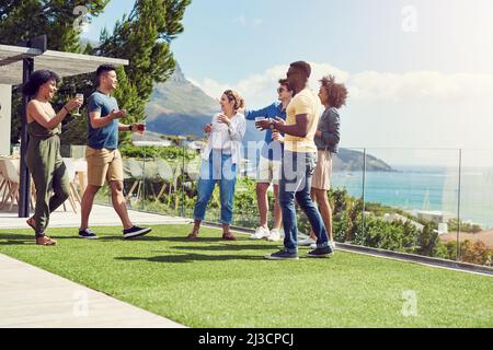 Tutti sono qui e pronti a divertirsi. Foto di un gruppo di amici che bevono bevande e si godono all'aperto durante le vacanze. Foto Stock