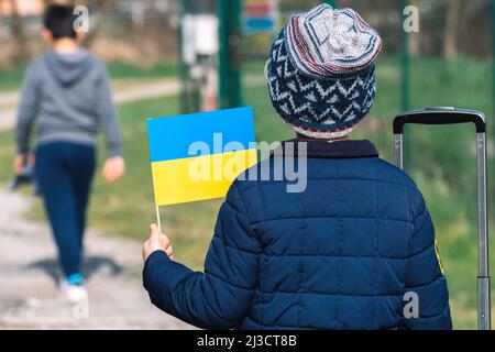 Bambini o bambini con abiti invernali, cappello e bandiera Ucraina, profilo del bambino è sulla bandiera. Guerra in Ucraina, causata da Putin e dalla Russia, rifugiati Foto Stock