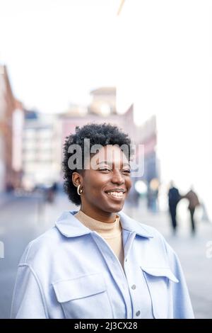 Focalizzato African American maschio braccio di tenuta di occhiali durante la lettura messaggio seduto nel parco Foto Stock