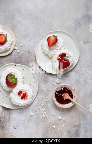 Da sopra meringa dolce bianca con fragole e gustosa marmellata servita su piatto su tavola di marmo grigio Foto Stock