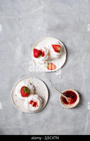 Da sopra meringa dolce bianca con fragole e gustosa marmellata servita su piatto su tavola di marmo grigio Foto Stock