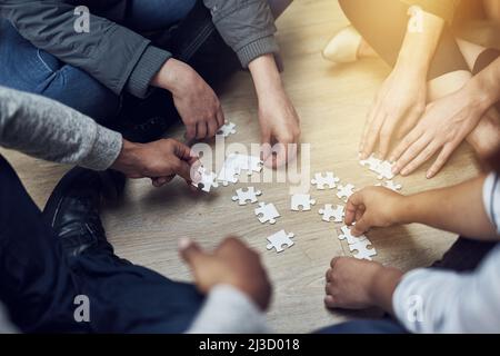 Inizi piccolo e sviluppi. Colpo di un gruppo di persone che costruiscono insieme un puzzle. Foto Stock