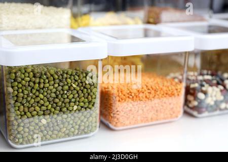 Contenitori trasparenti riempiti di legumi e cereali sulla mensola in cucina. Organizzazione di deposito di alimento sfuso Foto Stock