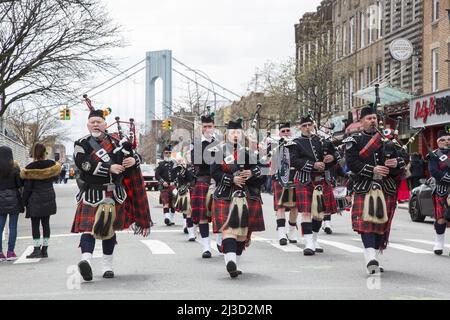 La Richmond County Pipes and Drums Band si esibirà nella sfilata Saint Patrick's Day a Brooklyn, New York. Torre del Ponte Verrazano sullo sfondo. Foto Stock