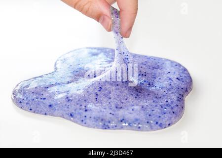 Giocare con slime testurizzato con bolle, stretching la sostanza gooey. Femmina teen mano che tiene blu brillante slime, schiacciandolo. Giocattolo liquido. Foto Stock