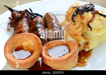 Salsiccia inglese e mash. Bangers, purè e budini dello Yorkshire con sugo di carne Foto Stock