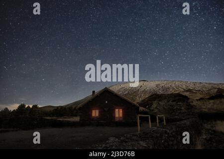 Notte stellata sull'Etna invernale e Rifugio Galvarina con finestre che illuminano, Sicilia Foto Stock