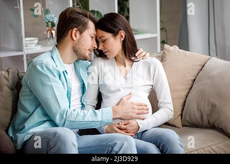 Coppia in attesa di un bambino, mentre il marito carezza il ventre della donna incinta. Foto Stock