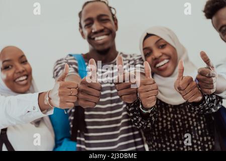 Ritratto di gruppo di studenti africani felici in piedi insieme su uno sfondo bianco e mostrando ok segno pollici su ragazze che indossano il Sudan tradizionale Foto Stock