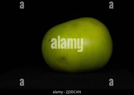 Una sola mela da cucina Bramley isolata su sfondo nero Foto Stock