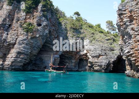 Laguna blu con barca da pesca vicino alla grotta nera Foto Stock