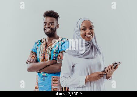 giovane donna di affari africana che indossa abiti tradizionali sudanesi mussulmani utilizzando un computer tablet isolato su bianco backgound studenti coppia Foto Stock