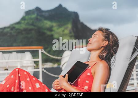 Crociera nave vacanza turista lettura libro sul baconly rilassarsi al sole prendere il sole sul lettino. Donna asiatica felice che dorme fuori abbronzarsi durante Foto Stock