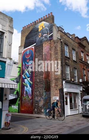 Ciclista e murales colorati su muro di edificio su Garrett St e Whitecross Street nel 2022 Londra EC1 Inghilterra Regno Unito Kathy DeWitt Foto Stock