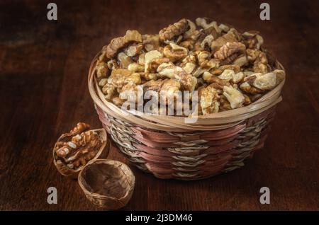 noci e nocciole in un cestino su sfondo di legno scuro Foto Stock