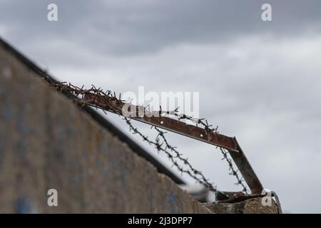 vista ravvicinata del vecchio filo spinato arrugginito in un clima cupo e sfocato Foto Stock