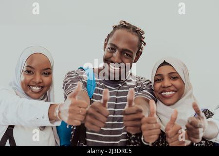 Ritratto di gruppo di studenti africani felici in piedi insieme su uno sfondo bianco e mostrando ok segno pollici su ragazze che indossano il Sudan tradizionale Foto Stock