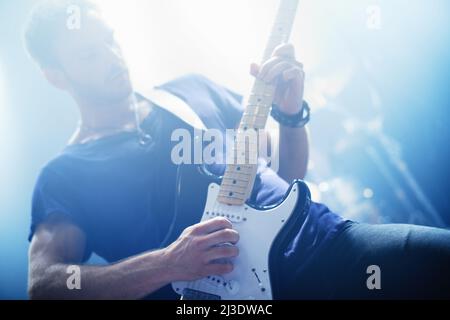 Fare musica. Vista ritagliata di una rock star che suona la chitarra durante un concerto - questo concerto è stato creato per il solo scopo di questa foto shoot, in scena Foto Stock