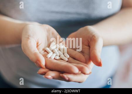 La mano di Womans sta tenendo le pillole. Sovradosaggio di capsule medicinali nel primo piano delle palme. Giornata mondiale della salute. Concetto di assistenza sanitaria. La donna prende il farmaco. Foto Stock