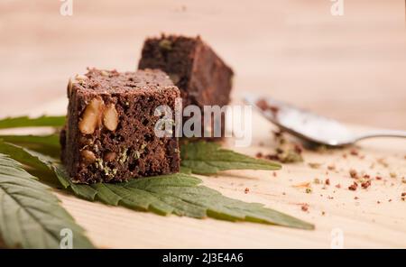 marijuana brownie su foglie di marijuana, dessert su tavola di legno. Foto Stock