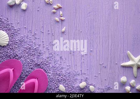 Estate al mare. Infradito in gomma magenta, pantofole su ciottoli con stelle marine, conchiglie e ciottoli, studio concept. Sfondo viola testurizzato, luogo Foto Stock