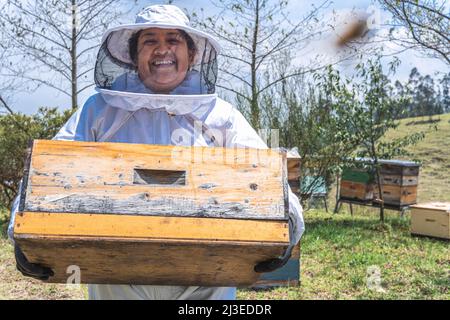 Ritratto di un apicoltore femmina che porta un nido d'ape con le api. Concetto di mietitura del miele Foto Stock
