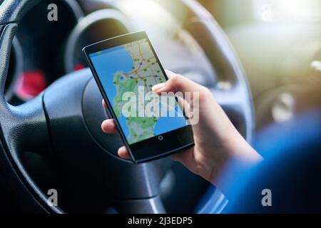 Ricerca del percorso più rapido. Scatto di una persona in auto utilizzando il telefono per trovare indicazioni. Foto Stock