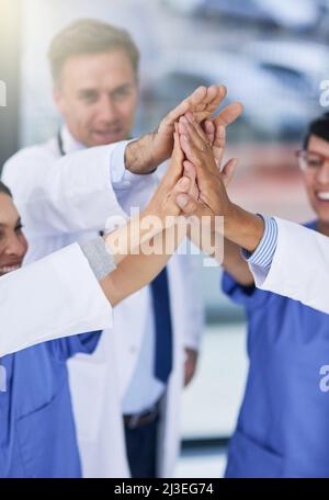 Il successo è il migliore se raggiunto come squadra. Closeup shot di medici che si danno a vicenda un alto cinque. Foto Stock