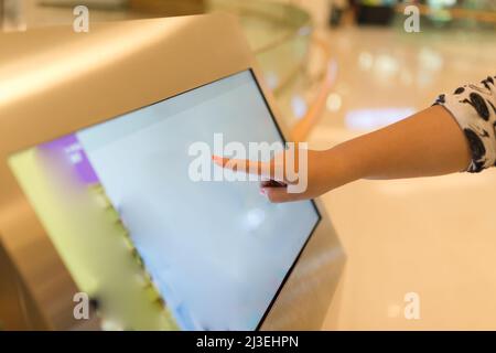 Primo piano della mano femminile sul banco informazioni del touch screen nel centro commerciale. Foto Stock