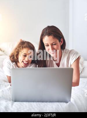 Rimanere occupati e divertirsi online. Scatto ritagliato di una madre e l'uso di un computer portatile insieme a casa al mattino. Foto Stock