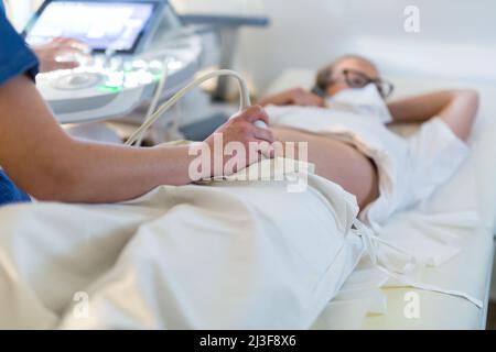 Primo piano di una donna incinta che esegue la scansione a ultrasuoni presso la clinica medica. Concetto di medicina e assistenza sanitaria Foto Stock